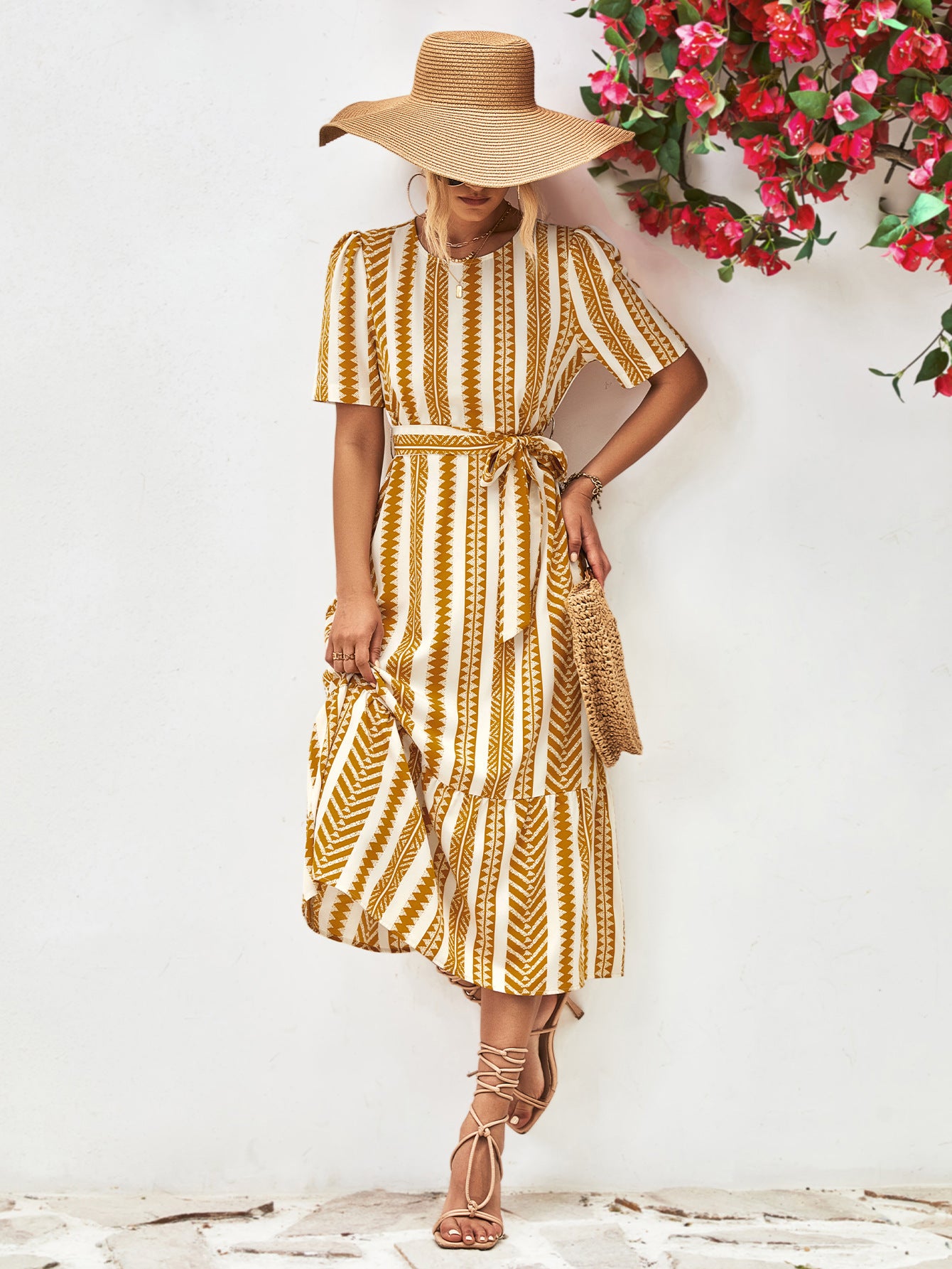 Gold striped round-neck puff sleeve dress with tied waist belt, walking stance front view.