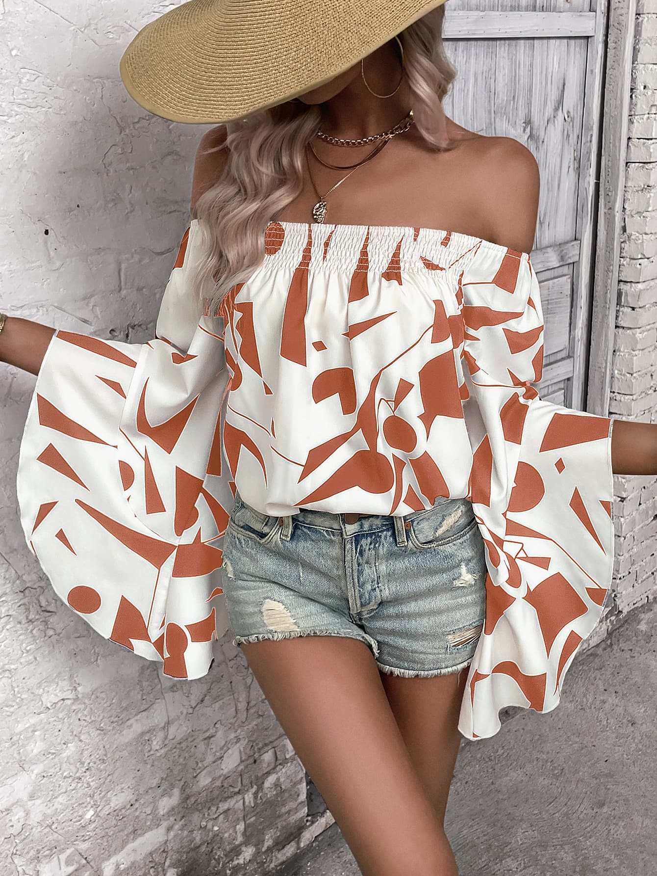 Off-shoulder bell sleeve blouse in white with orange abstract print