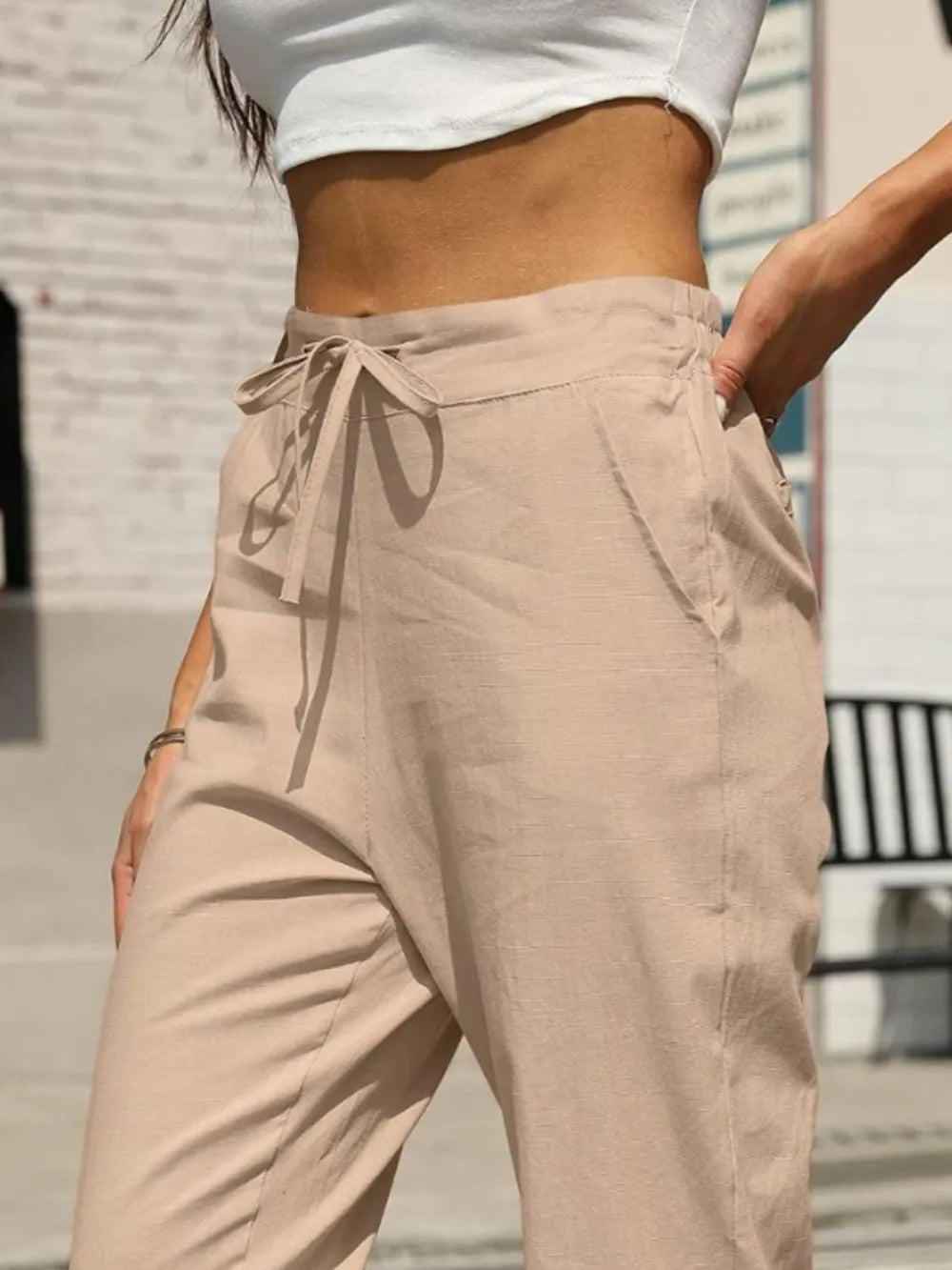 Beige elastic waist tapered pants with tied drawstring and side seam pockets