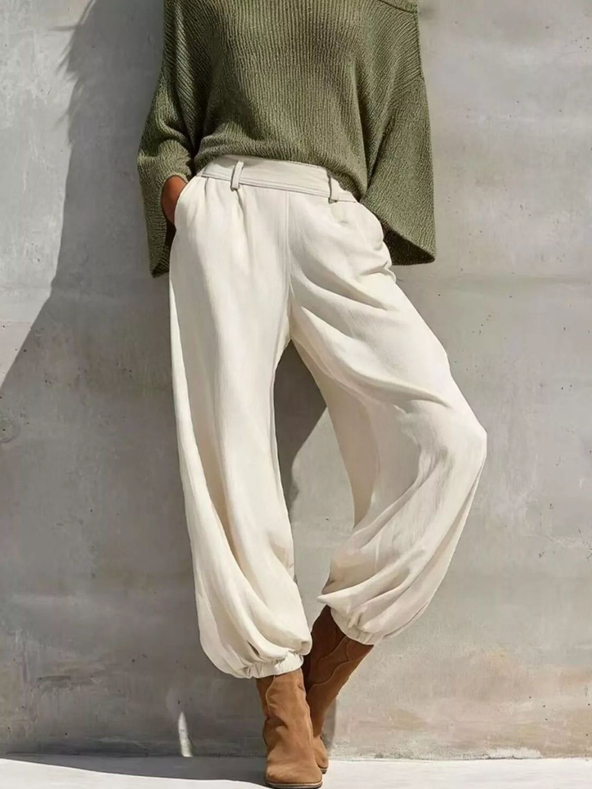 High-waisted white jogger pants with elastic cuffs paired with moss green knit top