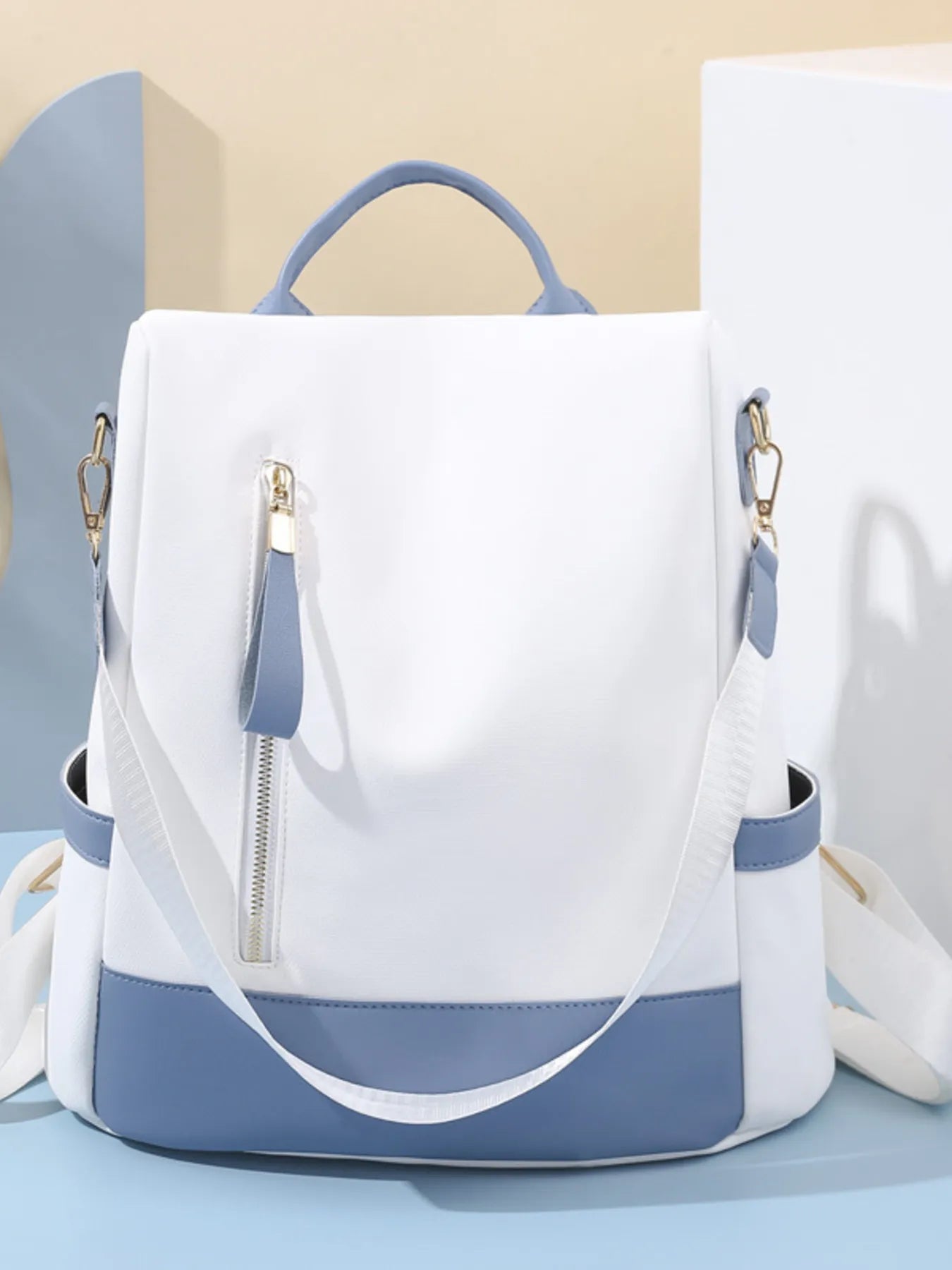 White and dusty blue color block convertible backpack bag with front zip pocket and top handles