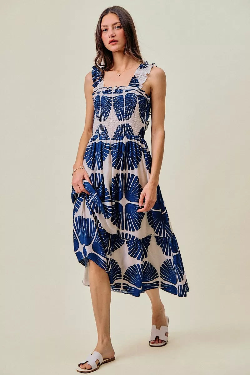 Three-quarter view of navy and white abstract print smocked bodice tiered midi dress