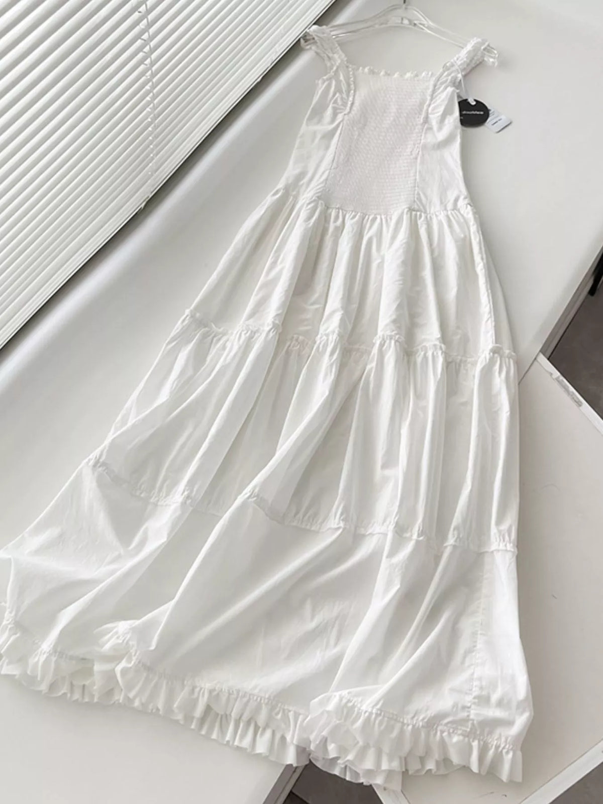 White cotton maxi dress with sleeveless ruffled square neck and flowing tiered skirt