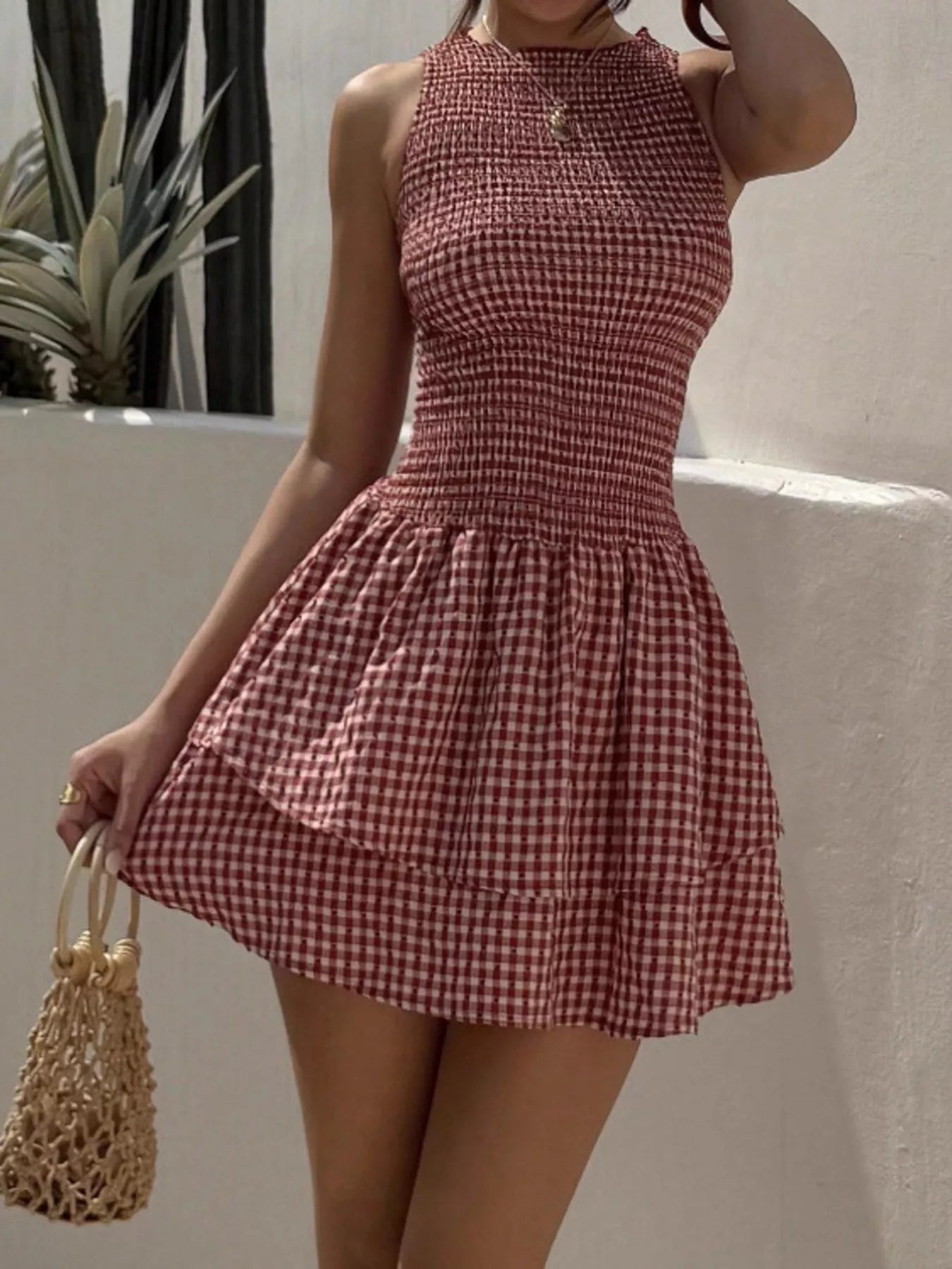 Gingham smocked mini dress in red and white checks; sleeveless with ruched bodice and flared ruffled skirt