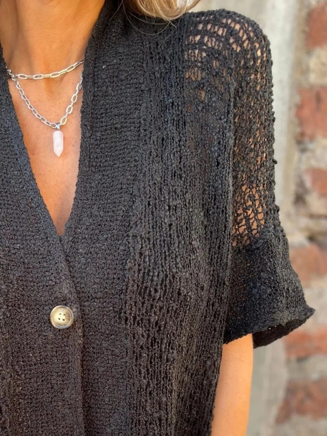 Openwork one-button cardigan with V-neck and three-quarter look sleeves in black, side view.