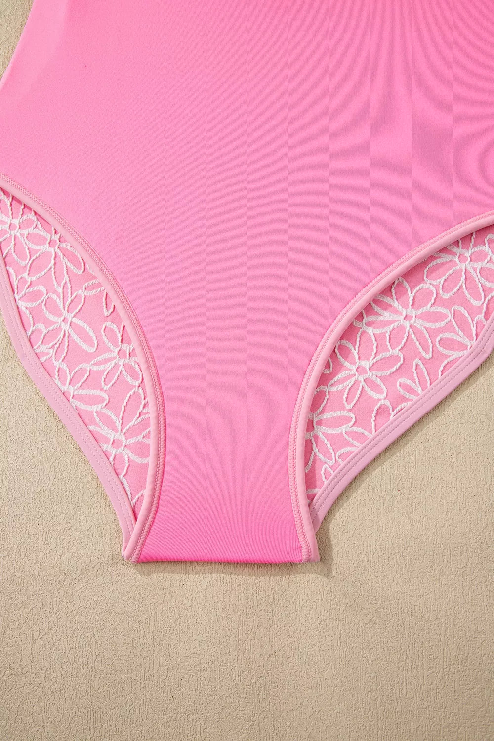 Blush pink halter one-piece swimsuit with floral lace trim at leg openings