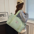 Light green large duffle travel bag with webbed handles and side straps