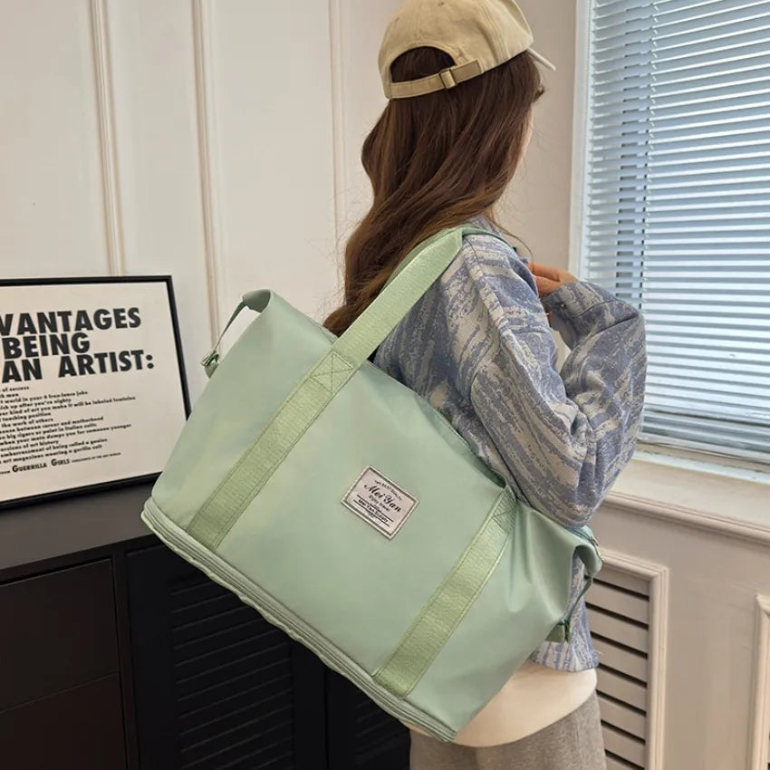 Light green large duffle travel bag with webbed handles and side straps