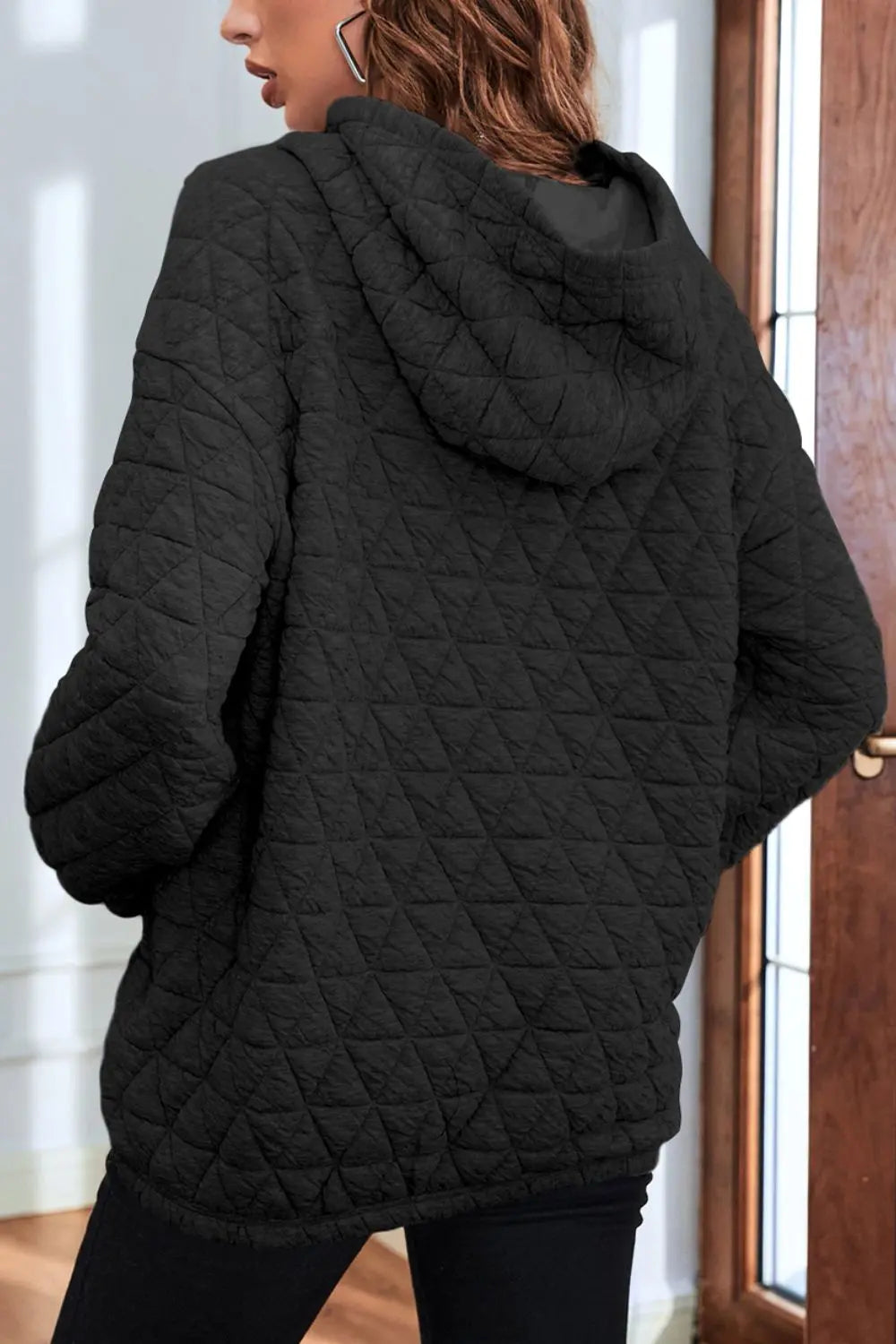 Black quilted long-sleeve hoodie, back view, with hood and front pocket