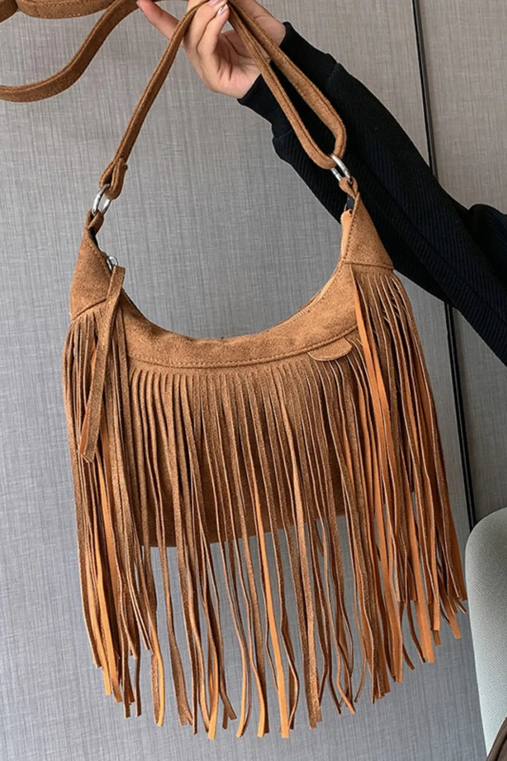 Tan suede fringe shoulder bag with adjustable strap and metal clasp rings