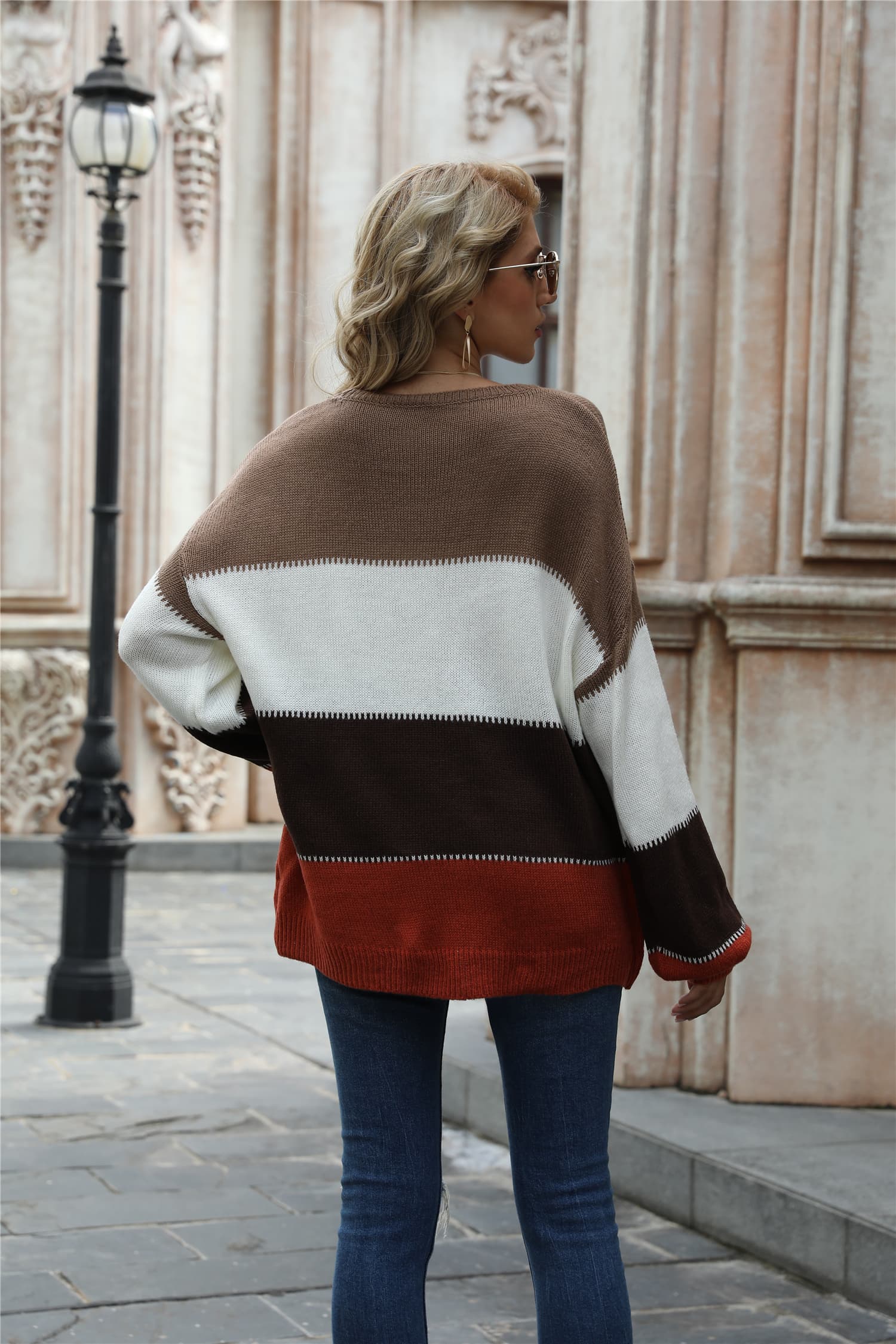 Back view color-block round-neck sweater with camel, white, dark brown, and rust bands.