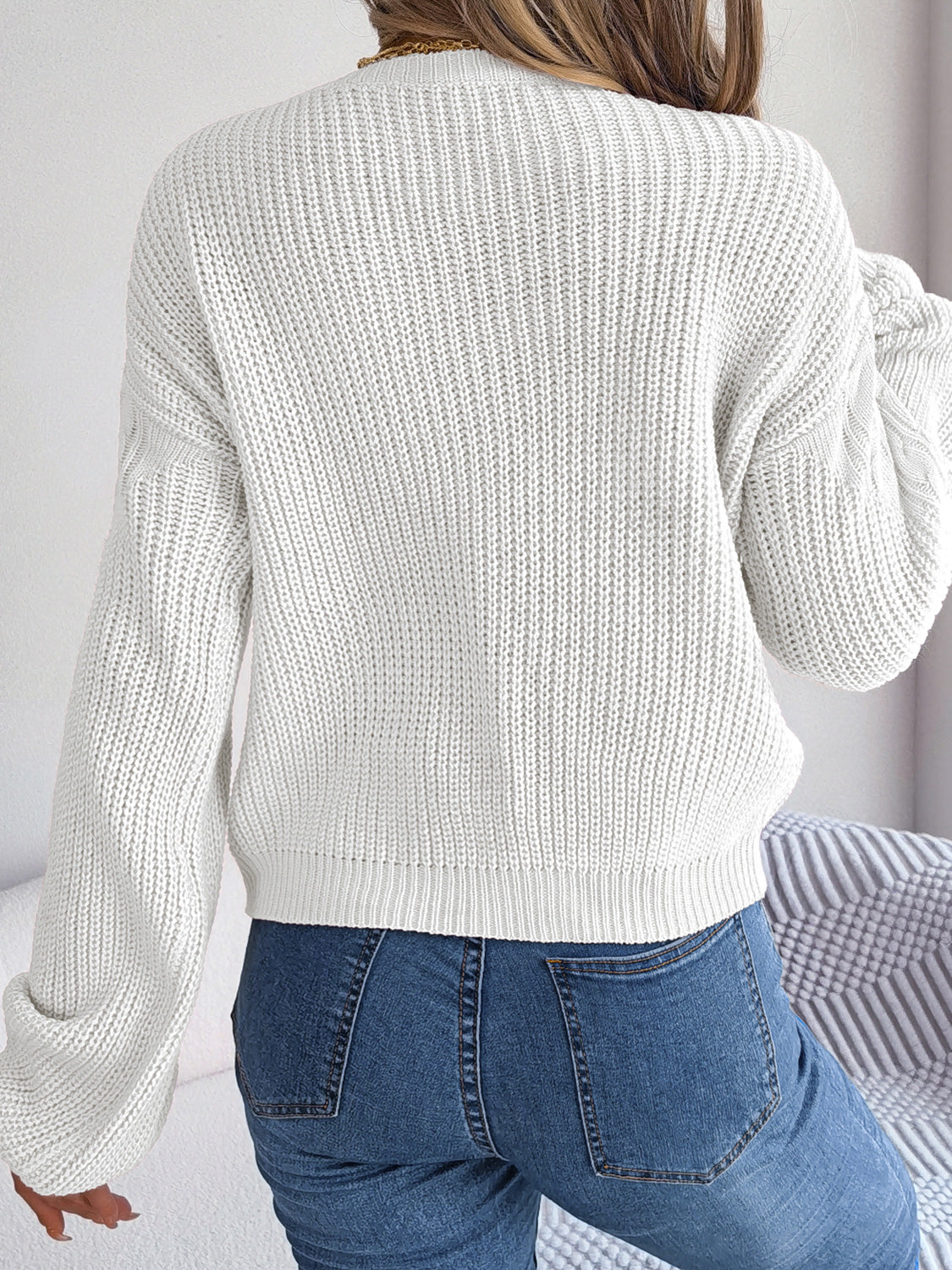 White cable-knit sweater back view with drop shoulder and cable knit texture