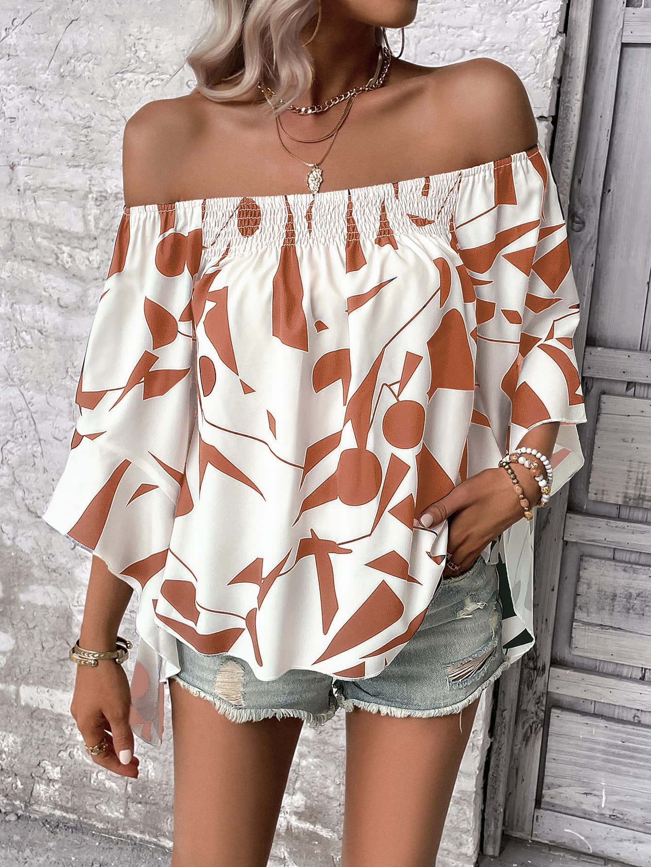 Off-shoulder bell sleeve blouse in white with orange abstract pattern