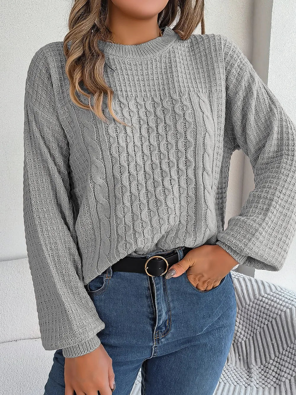 Charcoal cable-knit round-neck sweater with long sleeves and raised cable knit detail.