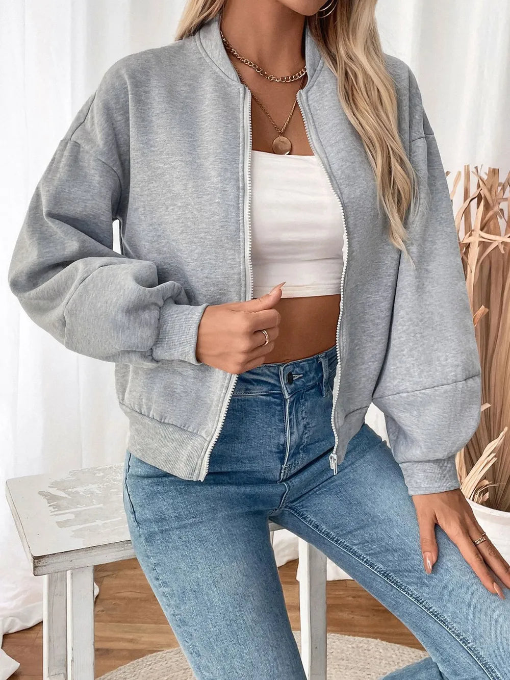 Light gray zip-up long sleeve sweatshirt with visible zipper and ribbed cuffs