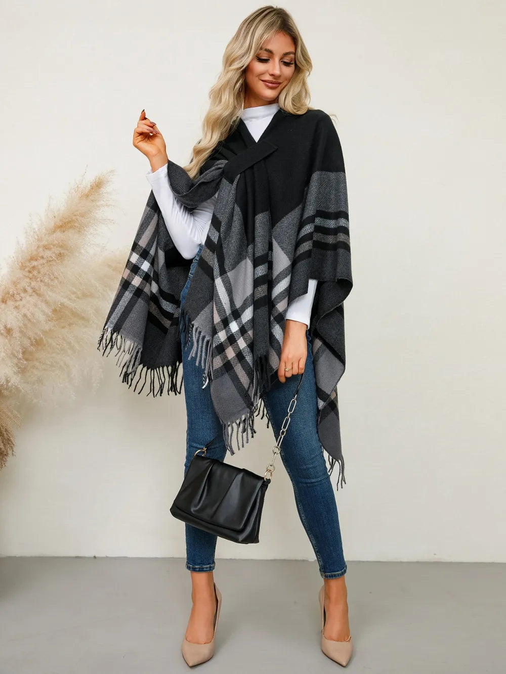 Plaid contrast fringe poncho in black and gray check design, draped over jeans