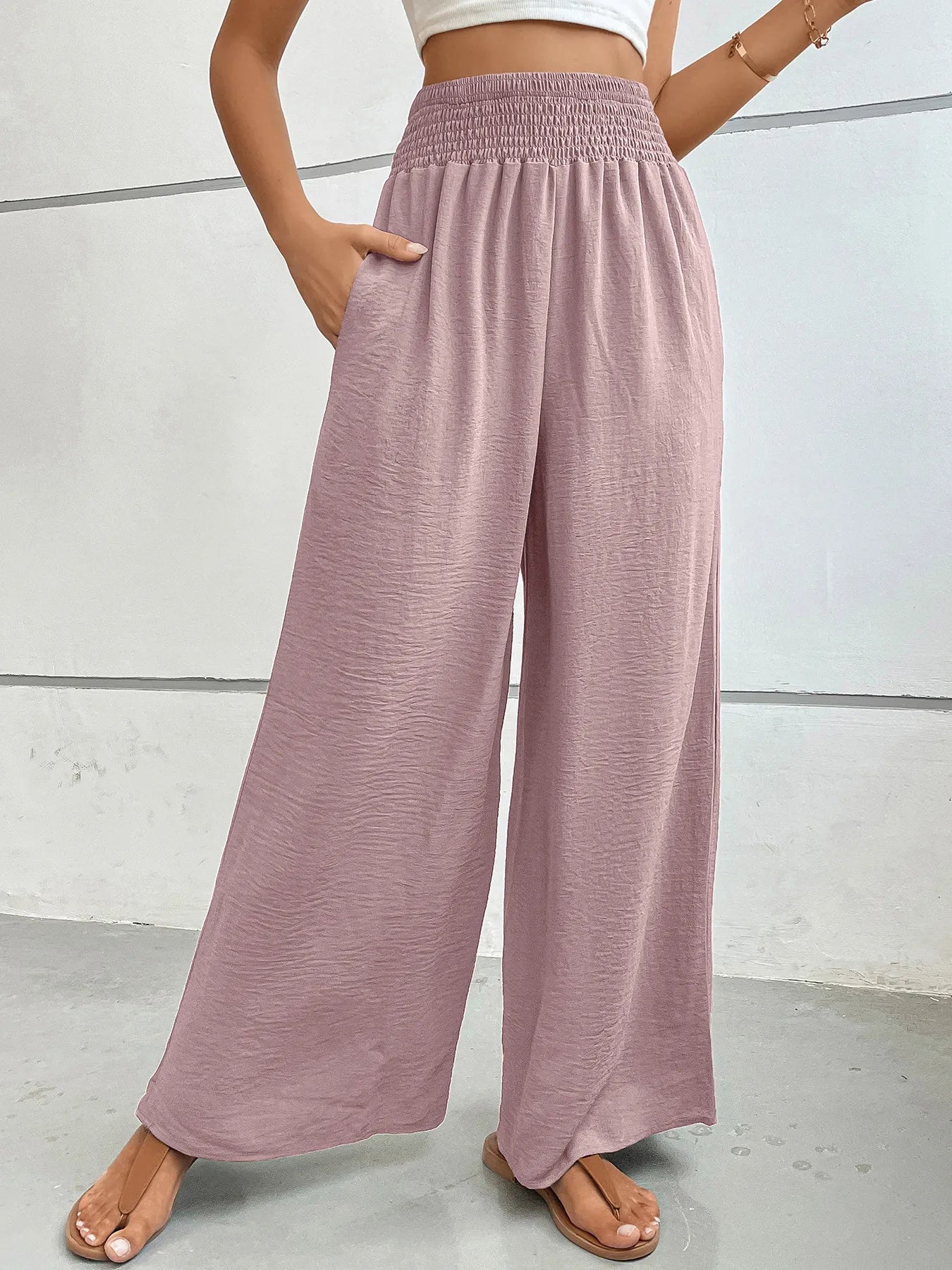 High-waisted wide-leg pants in dusty pink with smocked elastic waistband and flowing legs