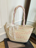 Woven straw shoulder bag with white lace bow and pastel pink handles