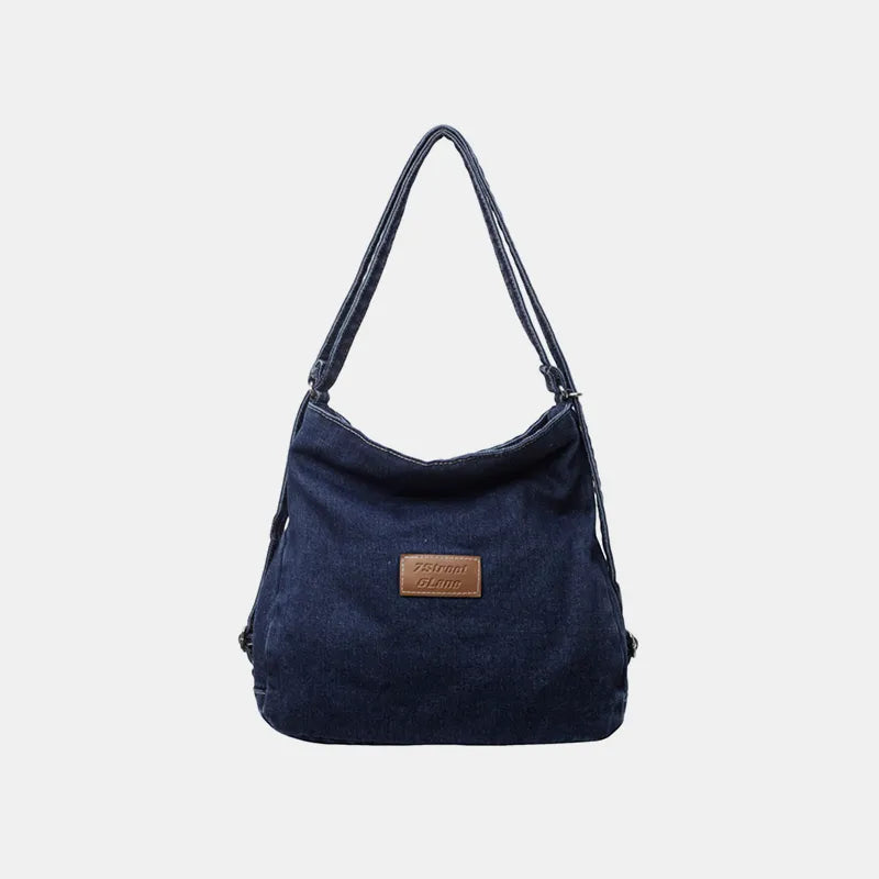 Navy denim shoulder bag with adjustable strap and rectangular leather logo patch