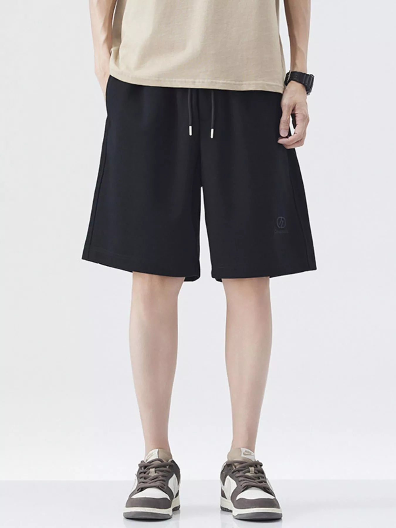 Black drawstring loose-fit shorts with front pockets and knee-length cut