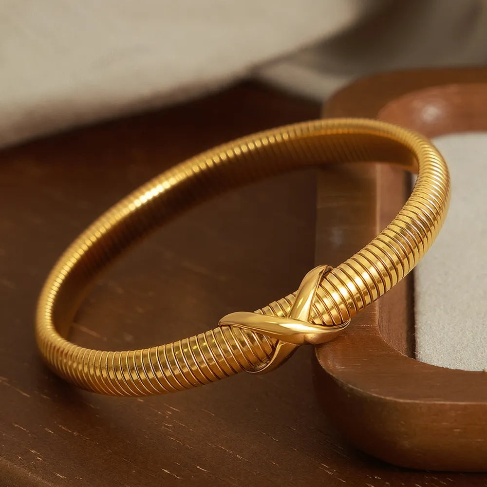 Gold spring coil bracelet with braided knot detail across coil