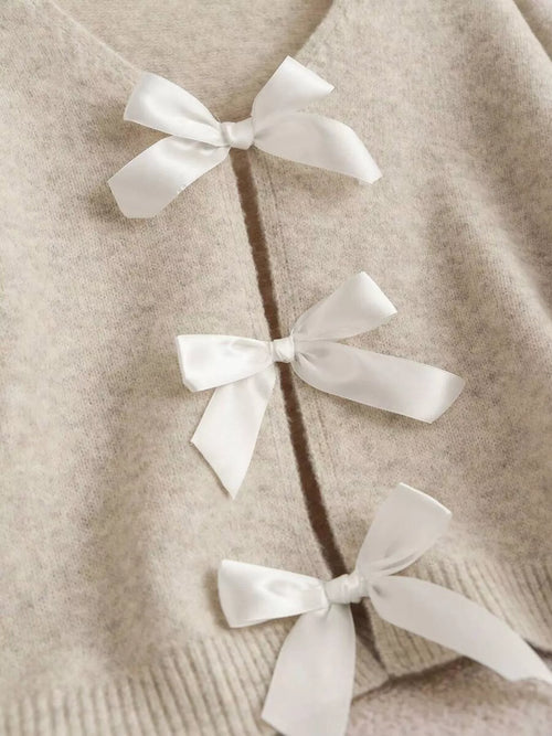 Light beige V-neck knit cardigan detail with three white ribbon bows