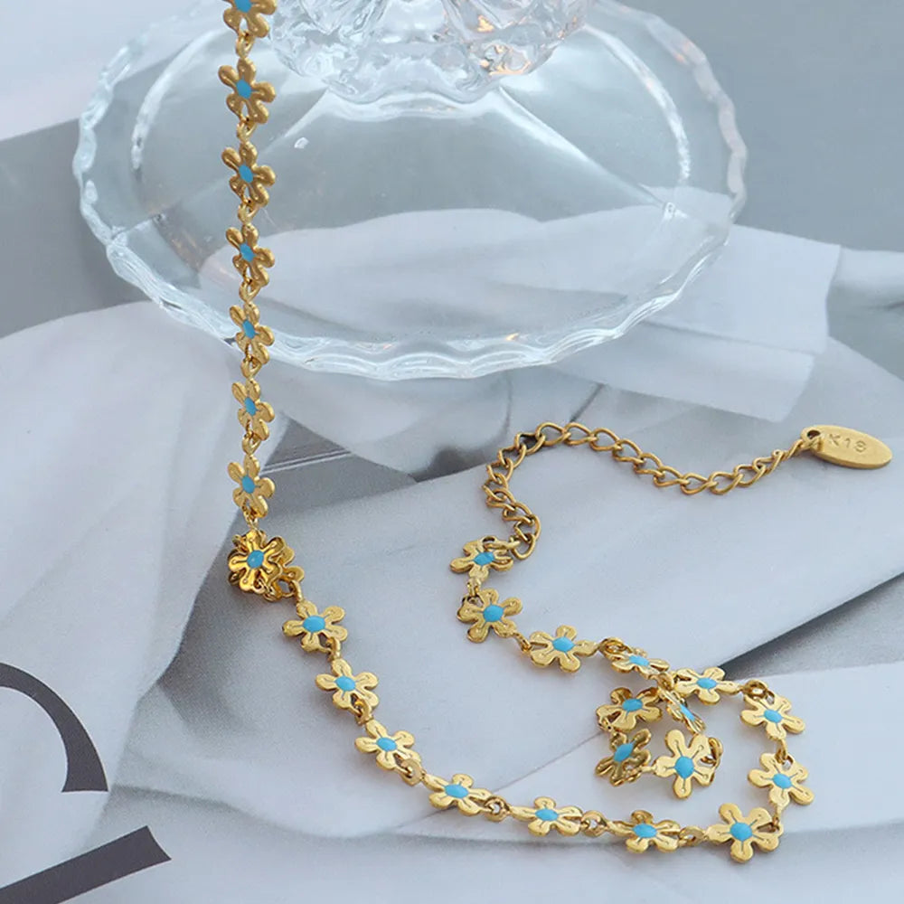 Gold-tone necklace with dangling flower charms and turquoise-blue bead clovers, clasp visible