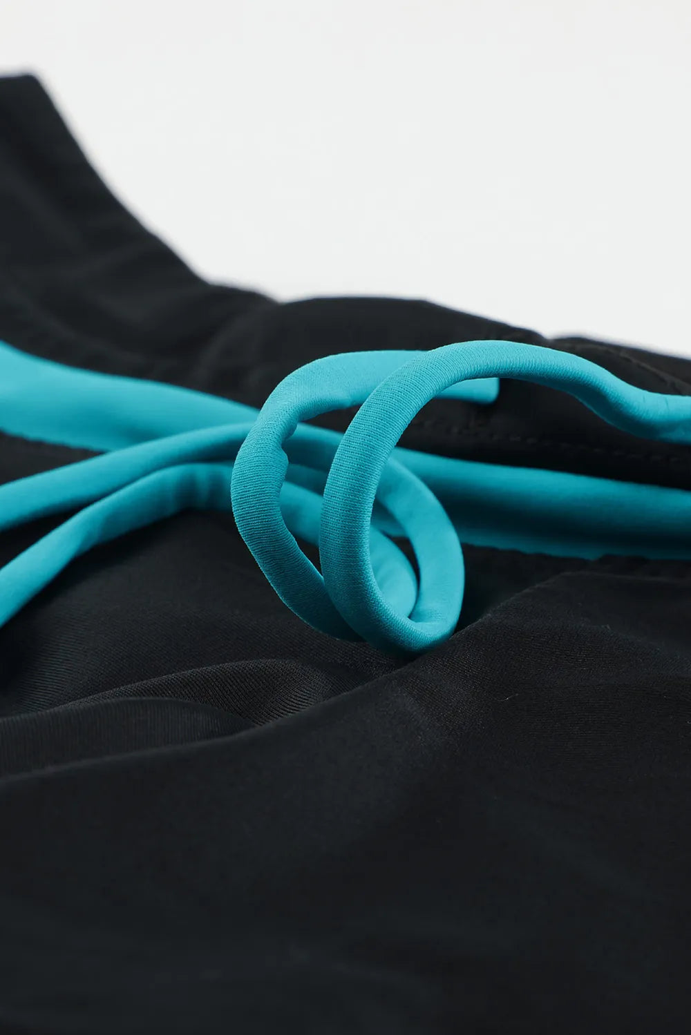 Black swim shorts close-up with turquoise drawstring and braided cord