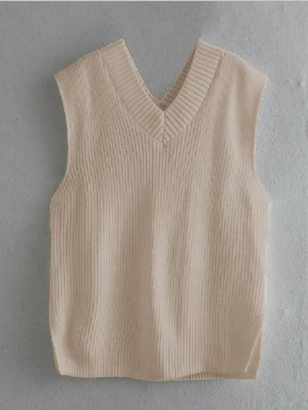 Cream ribbed V-neck sleeveless sweater vest, displayed flat with straight hem.