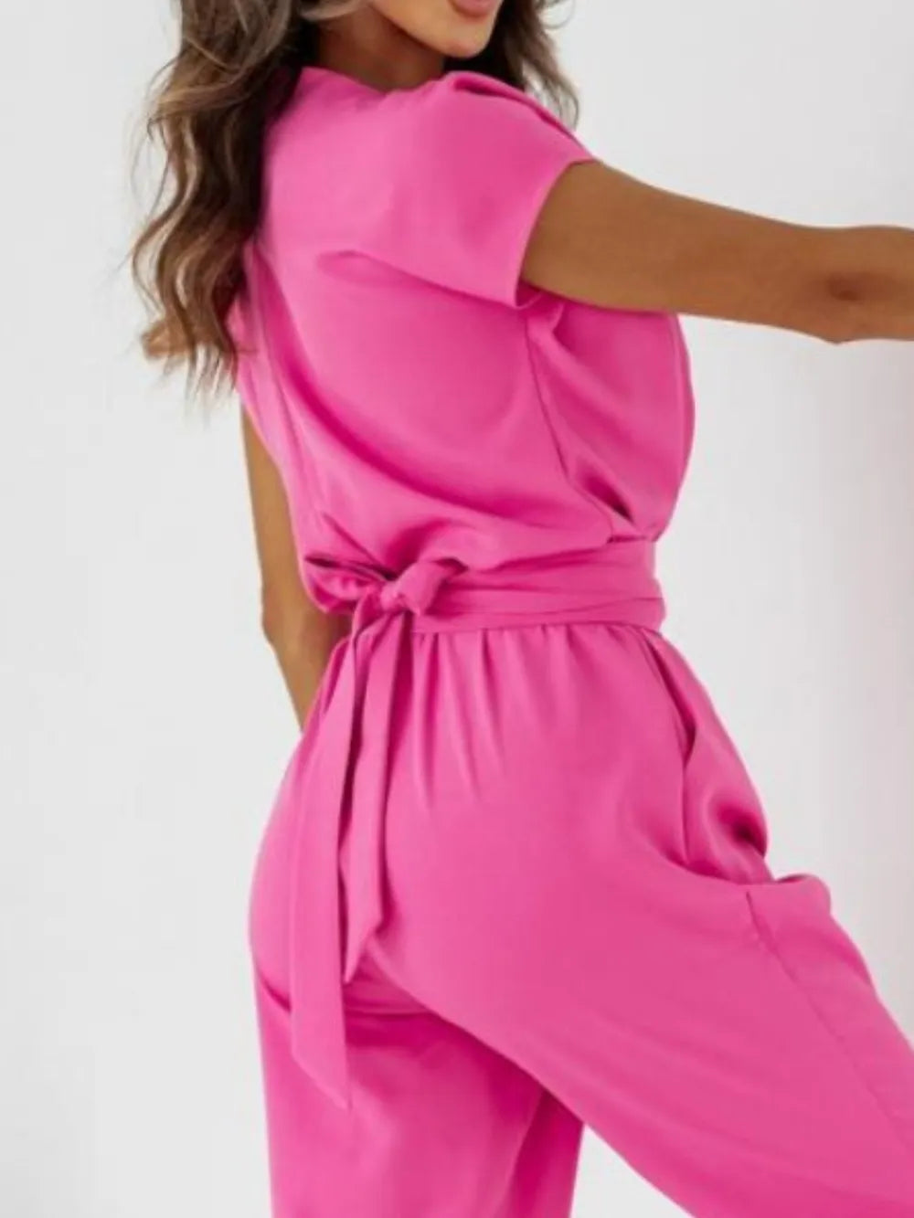 Hot pink surplice V-neck cap sleeve jumpsuit with tied waist and draped neckline