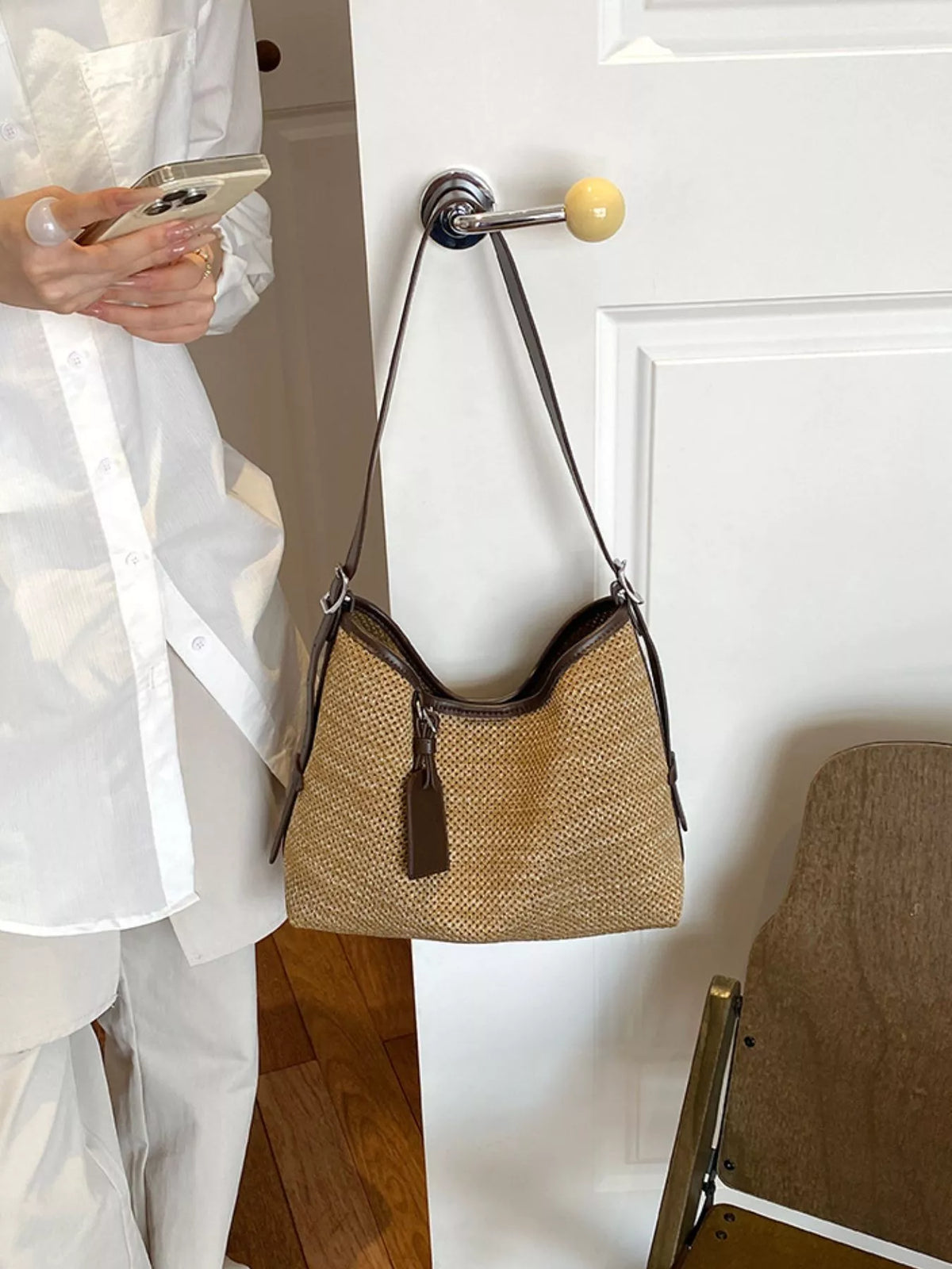 Camel woven shoulder bag with dark trim, front pockets, and hanging tag
