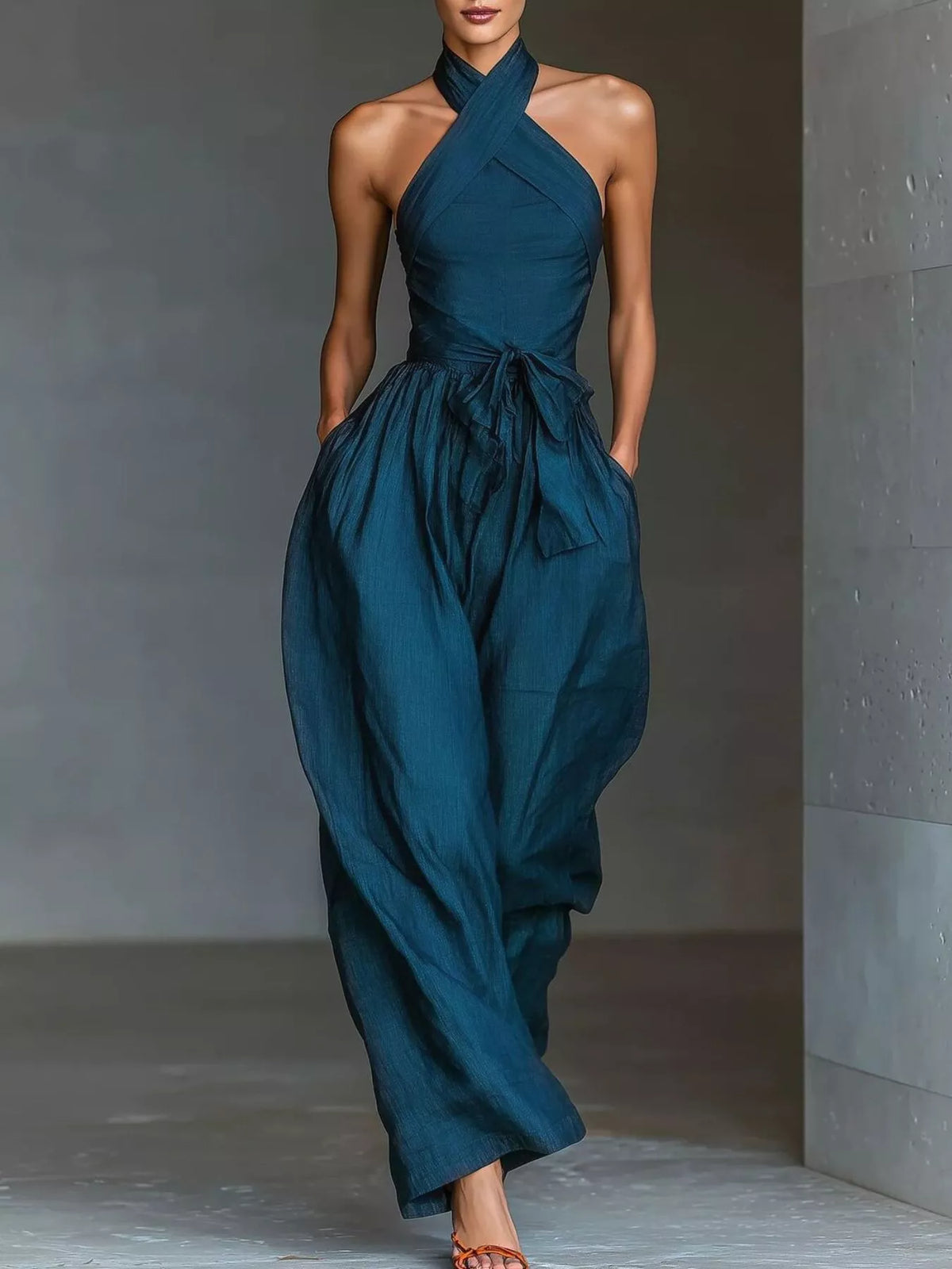Blue halter-neck jumpsuit with gathered waist tie and wide, flowing legs