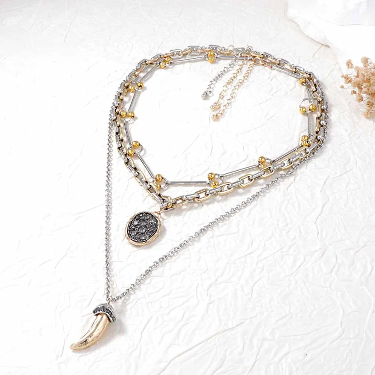 Layered pendant necklaces with round dark medallion and horn charm, short and long chains
