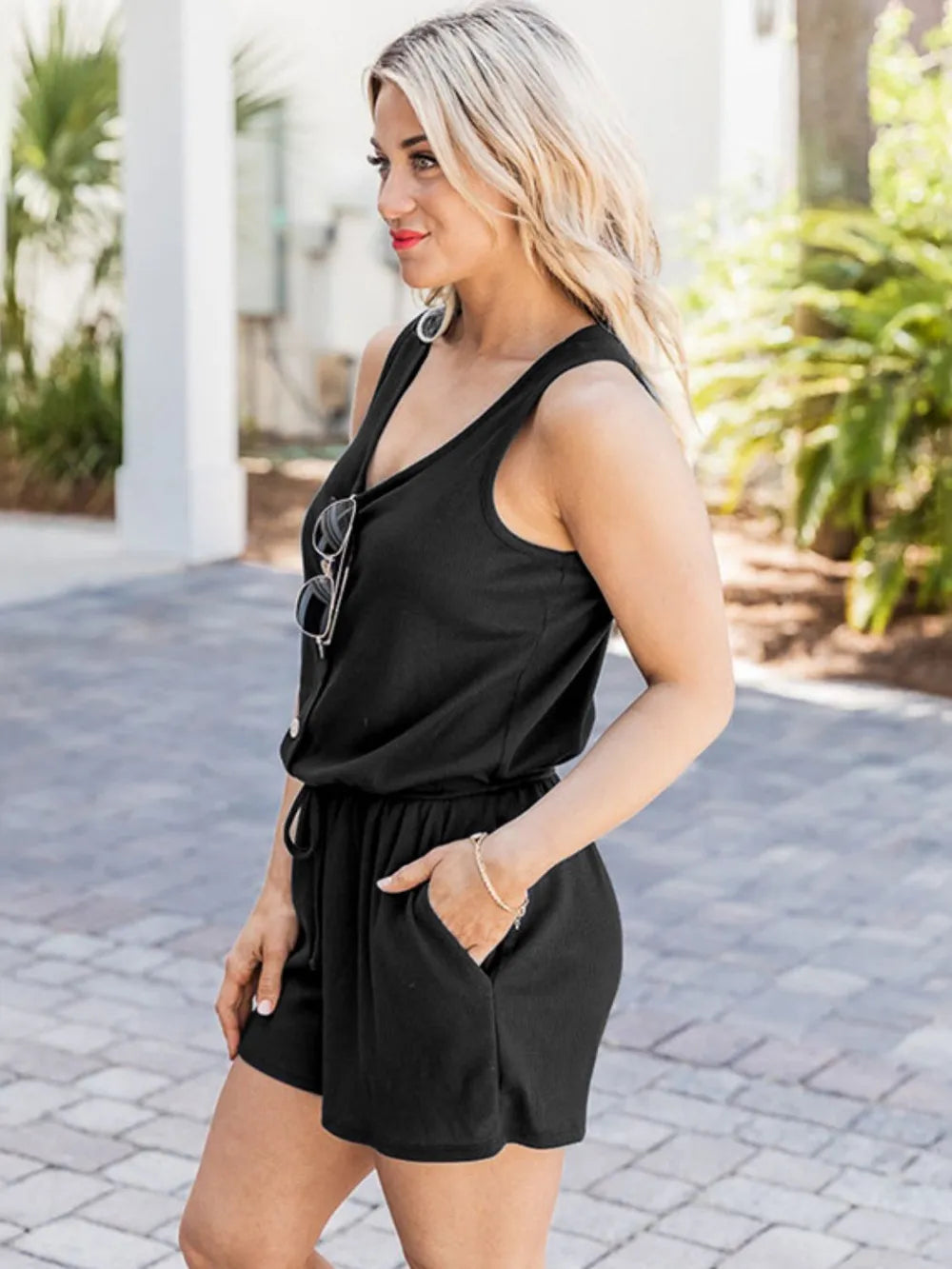 Black scoop-neck romper with wide straps, button detail, and drawstring waist