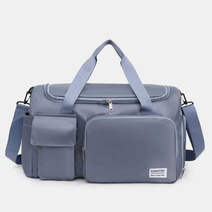 Large travel duffle bag with detachable straps, dusty blue with front zip compartment.