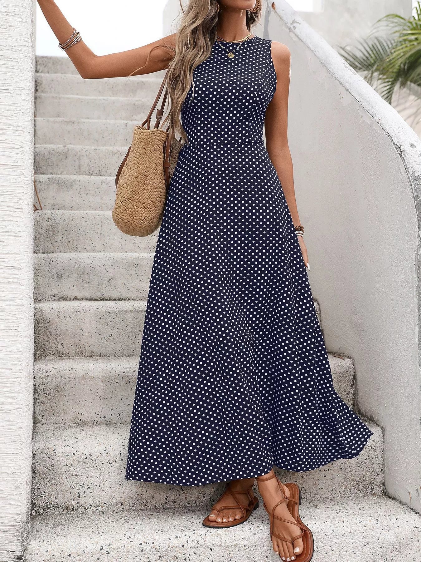Cedar & Moore Sleeveless Polka Dot Maxi Dress, navy with white polka dots, styled with straw tote and tan sandals