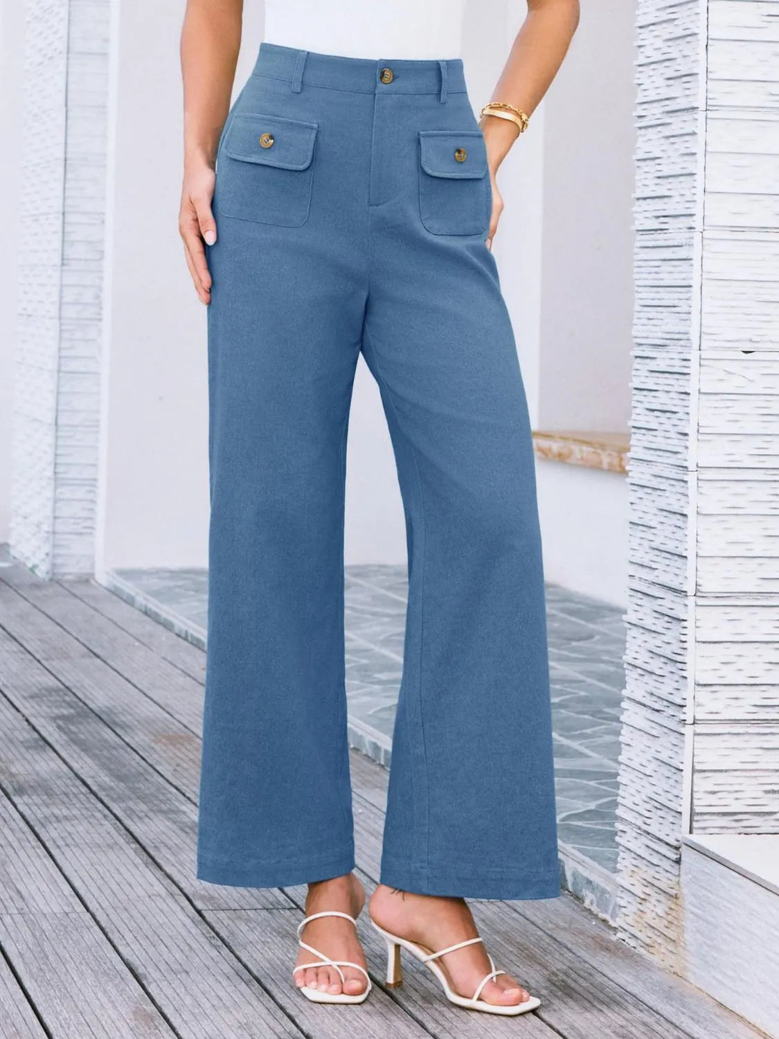 High-waist wide-leg pants, medium blue with flap front pockets and gold buttons.