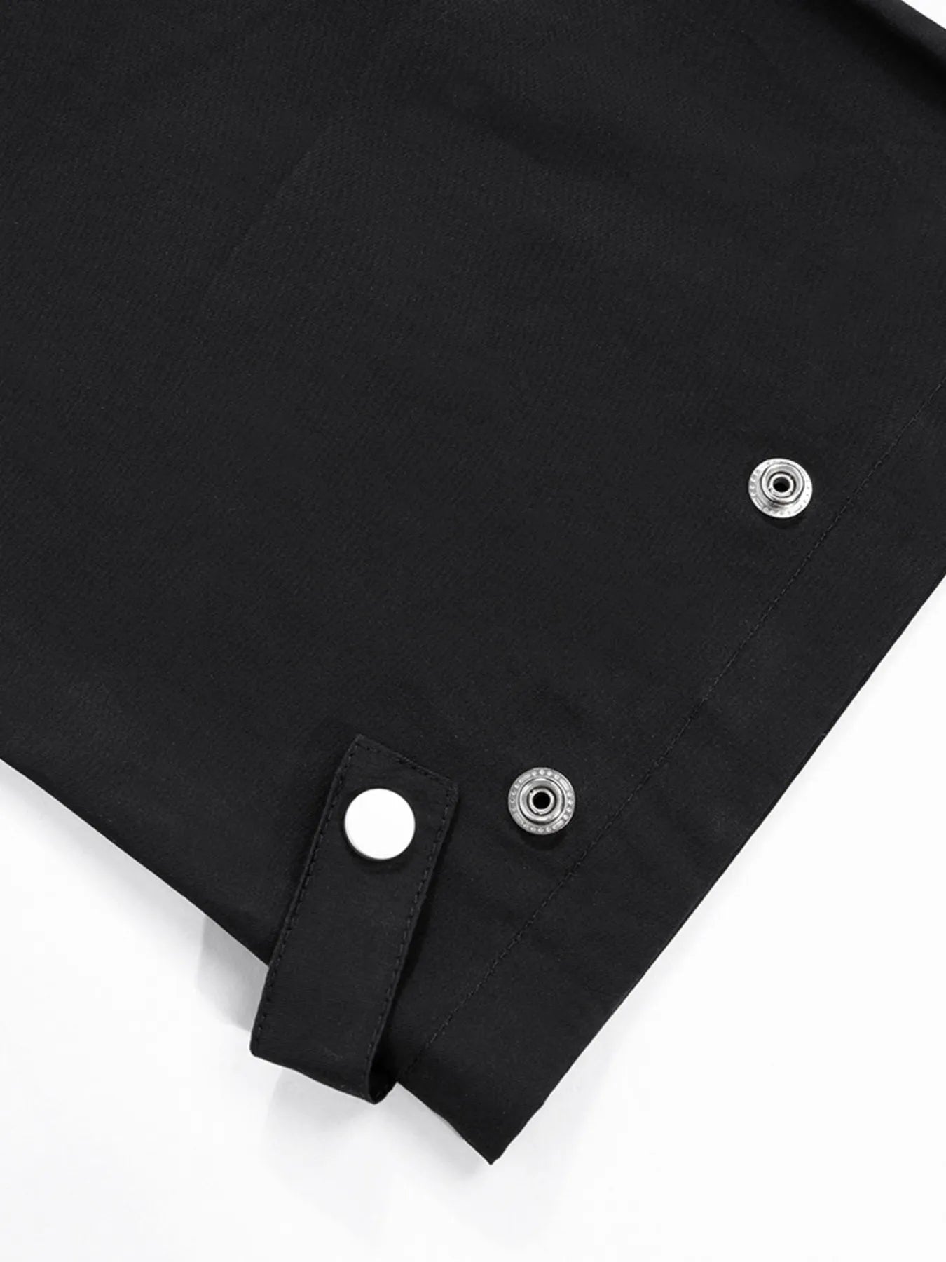 Black cargo pant hem with snap buttons and adjustable tab strap, close-up.