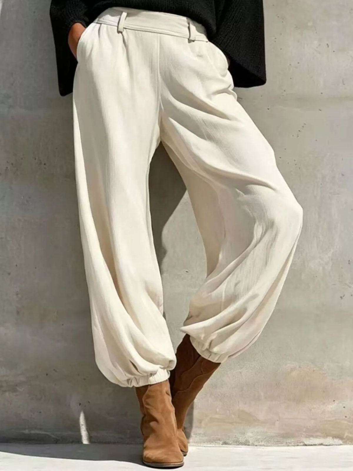 High-waisted white jogger pants with elastic cuffs paired with black knit top