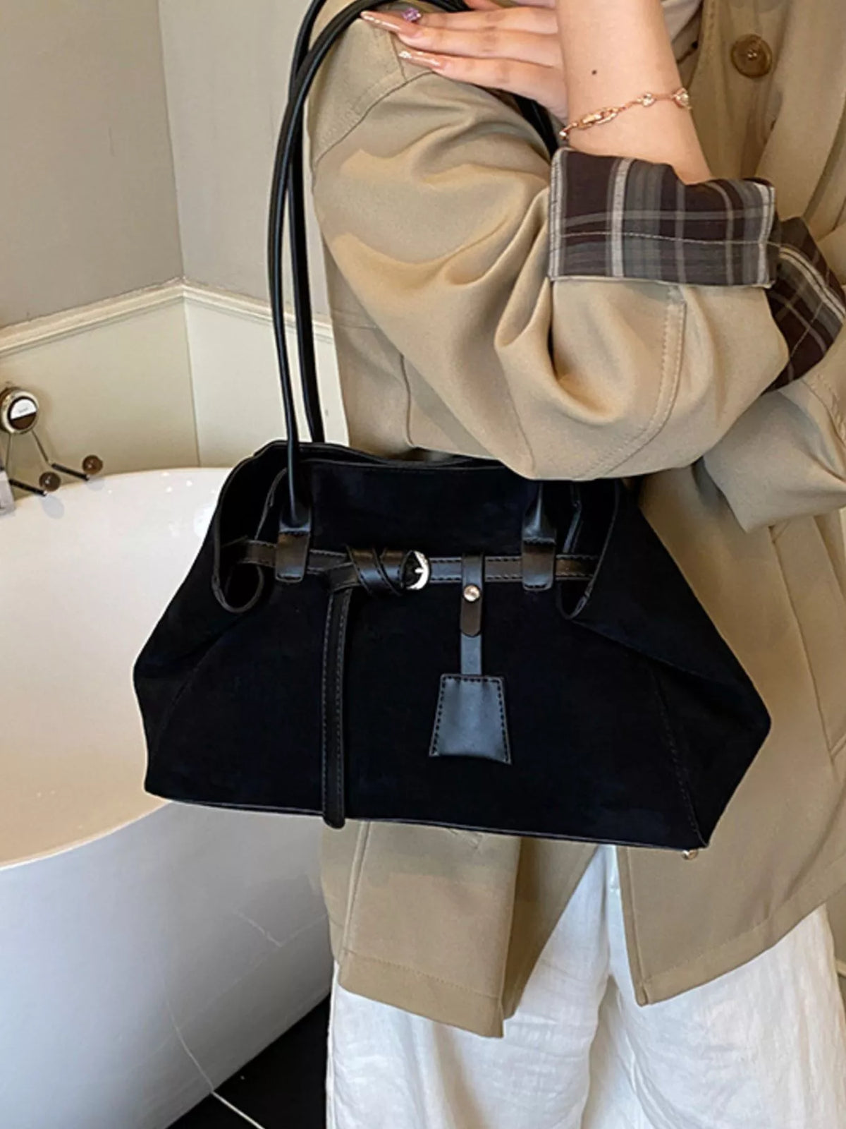Black suede shoulder bag with buckle strap, structured top handles, and front patch pocket