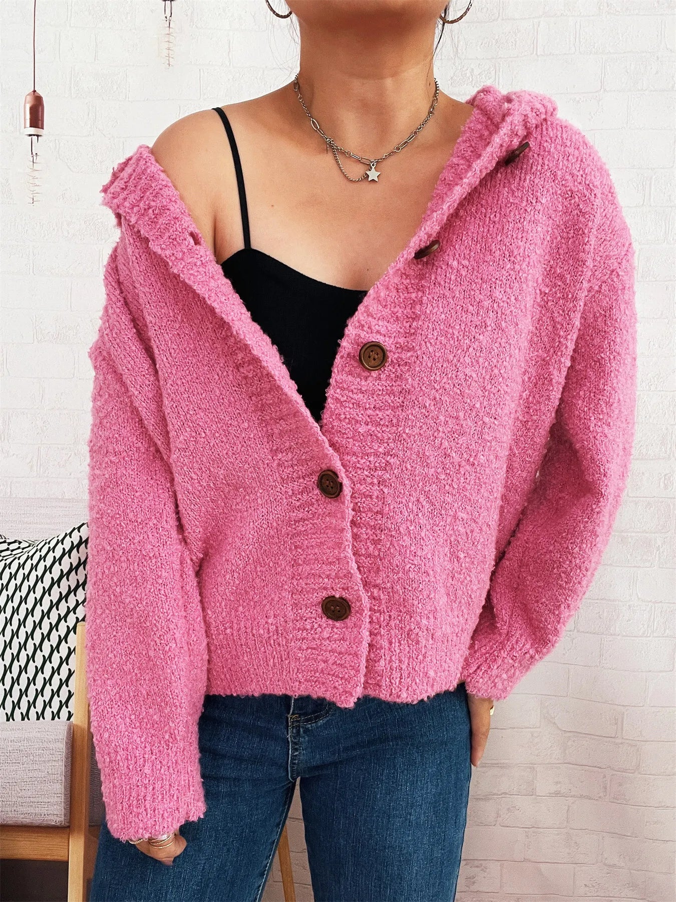 Pink hooded cardigan sweater with front buttons, worn over a black camisole, long sleeves.