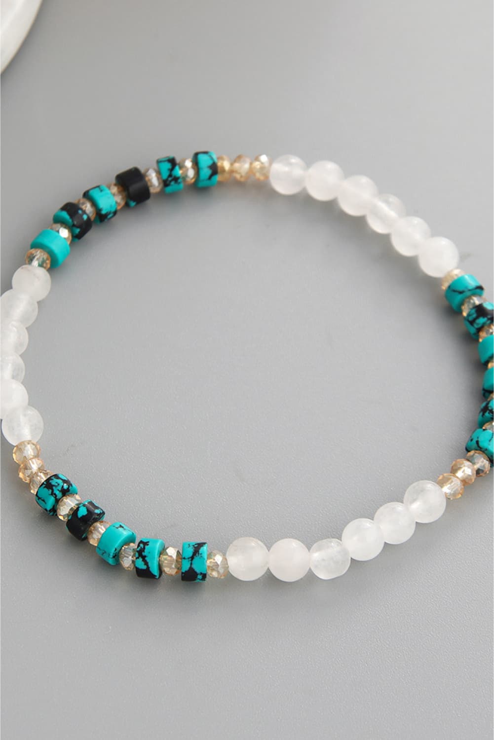 Crystal and natural stone bracelet with white beads, teal stones, and gold details