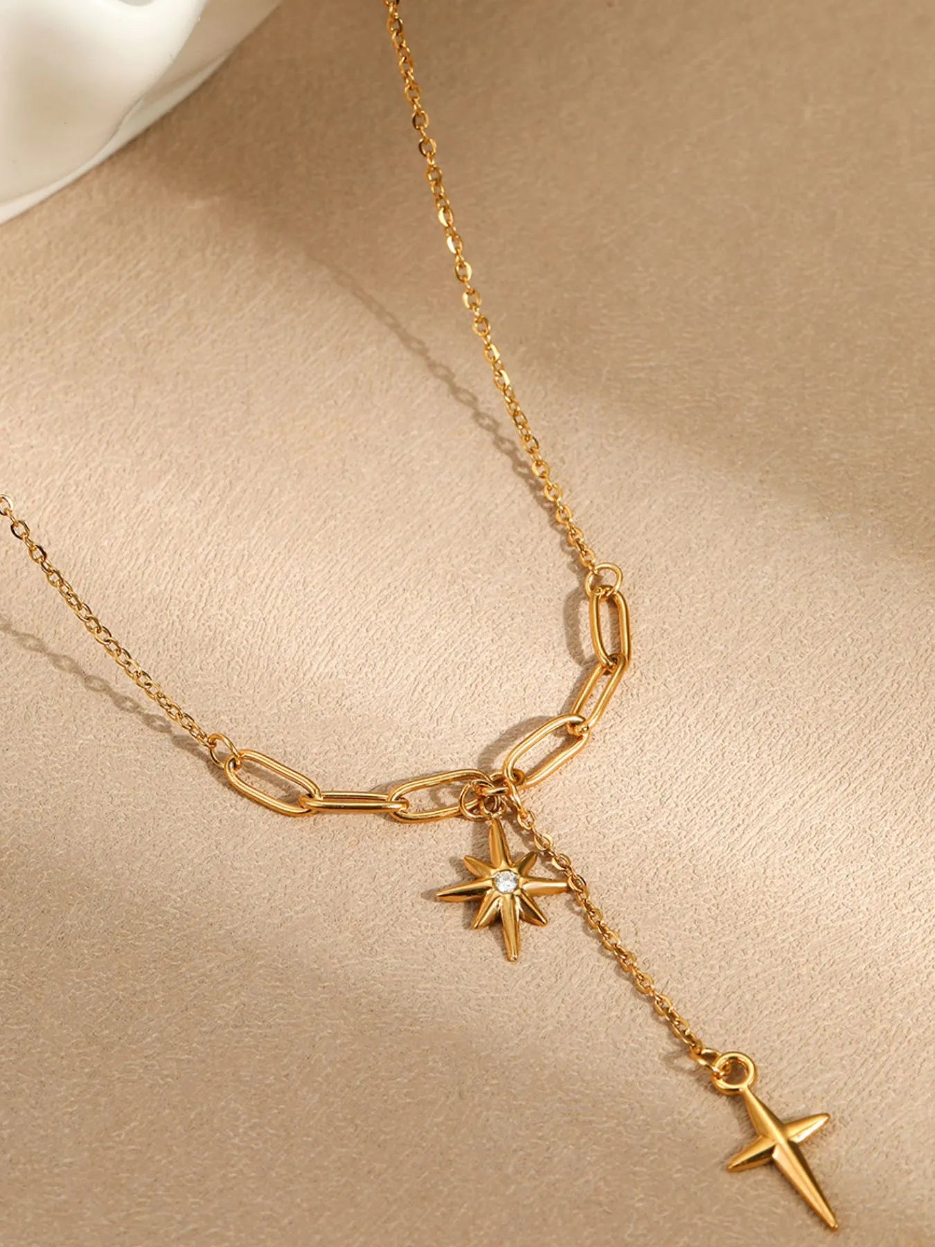 Gold-plated pendant necklace close-up with star charm and cross charm