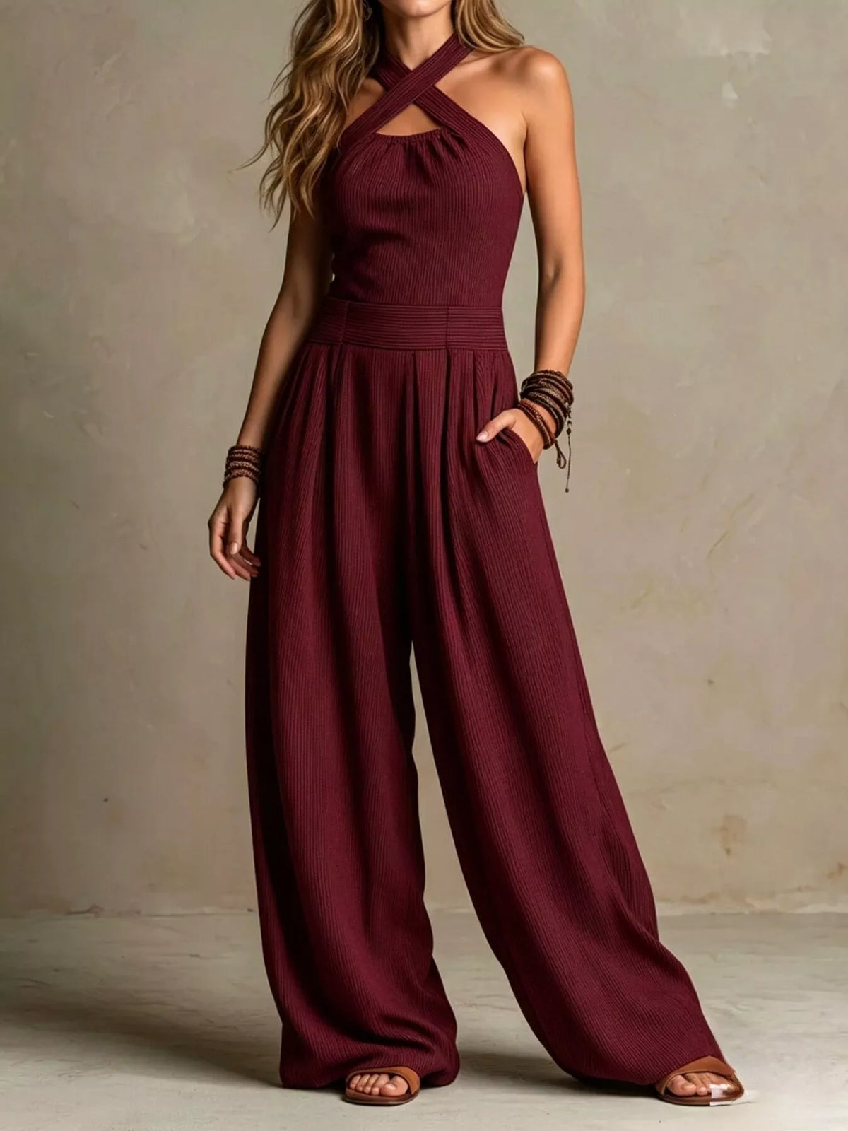 Burgundy halter-neck wide-leg jumpsuit with sleeveless bodice and gathered waist.