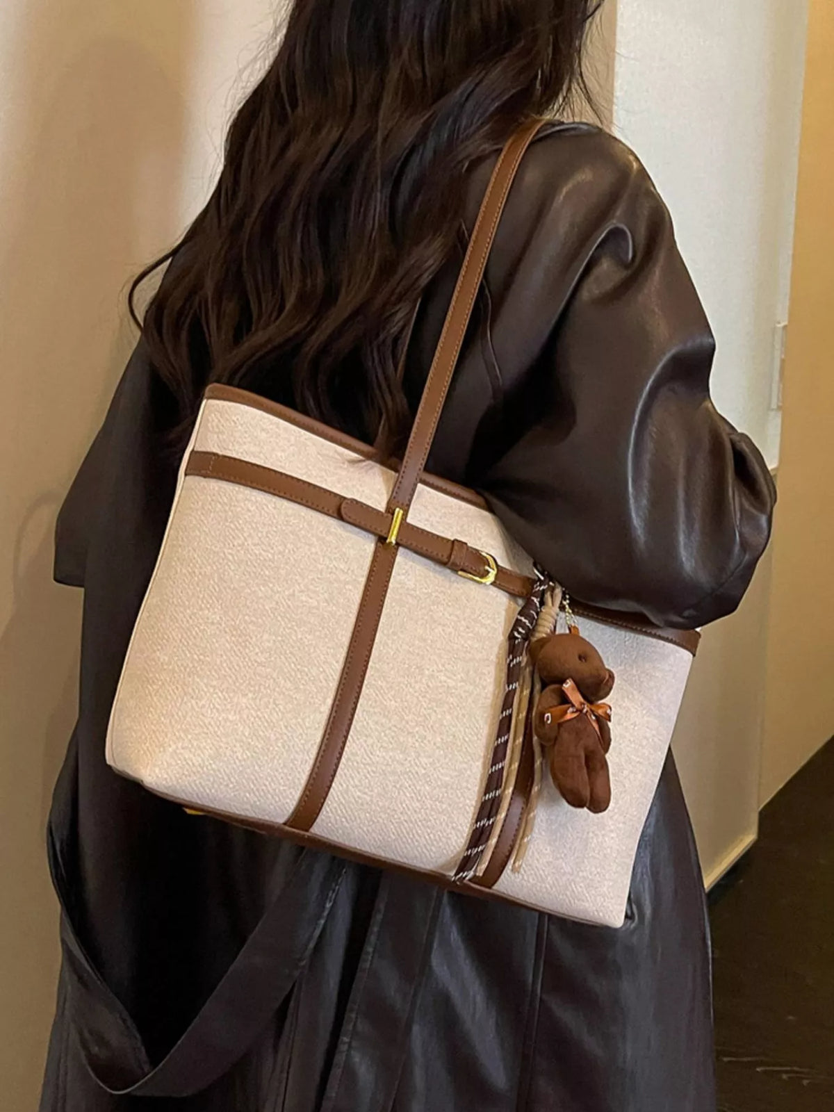 Off-white tote bag with brown straps and hanging teddy keychain with tassel