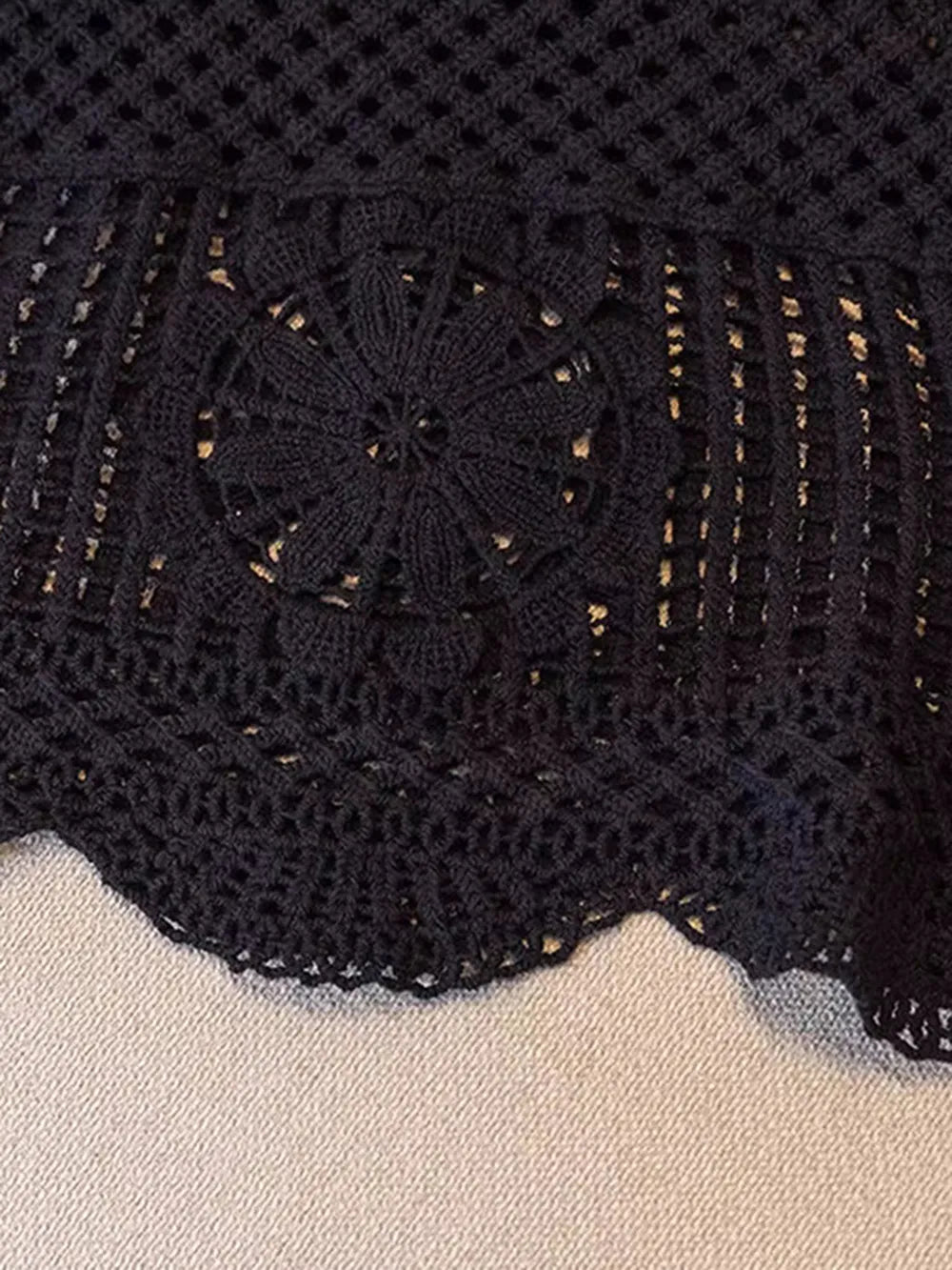 Black crochet tank close-up with floral openwork motif and gold-toned specks