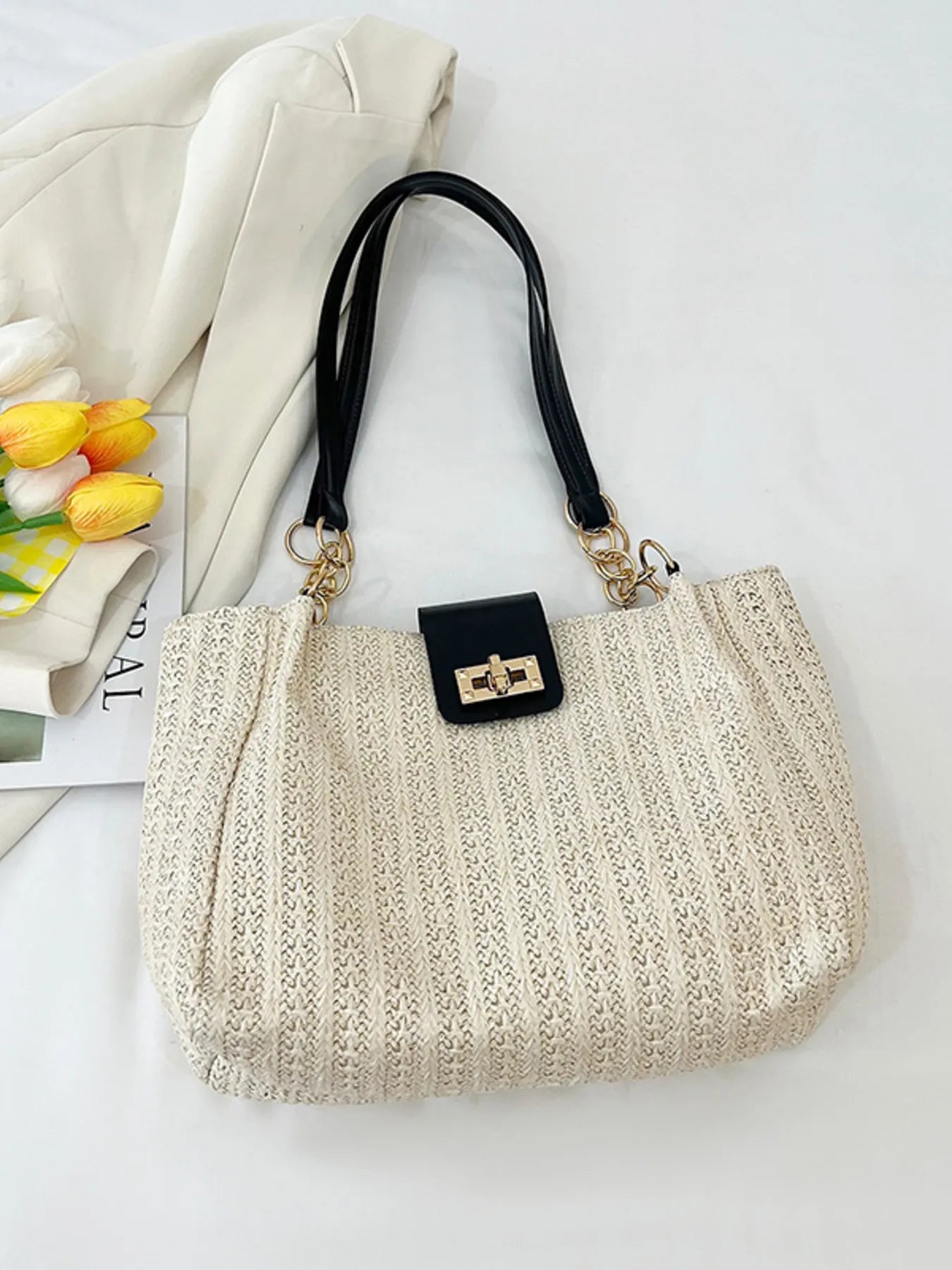 Woven straw shoulder bag in beige with black top handles and gold clasp hardware