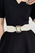 Ivory elastic belt with multicolor leaf buckle, worn at waist over dark dress