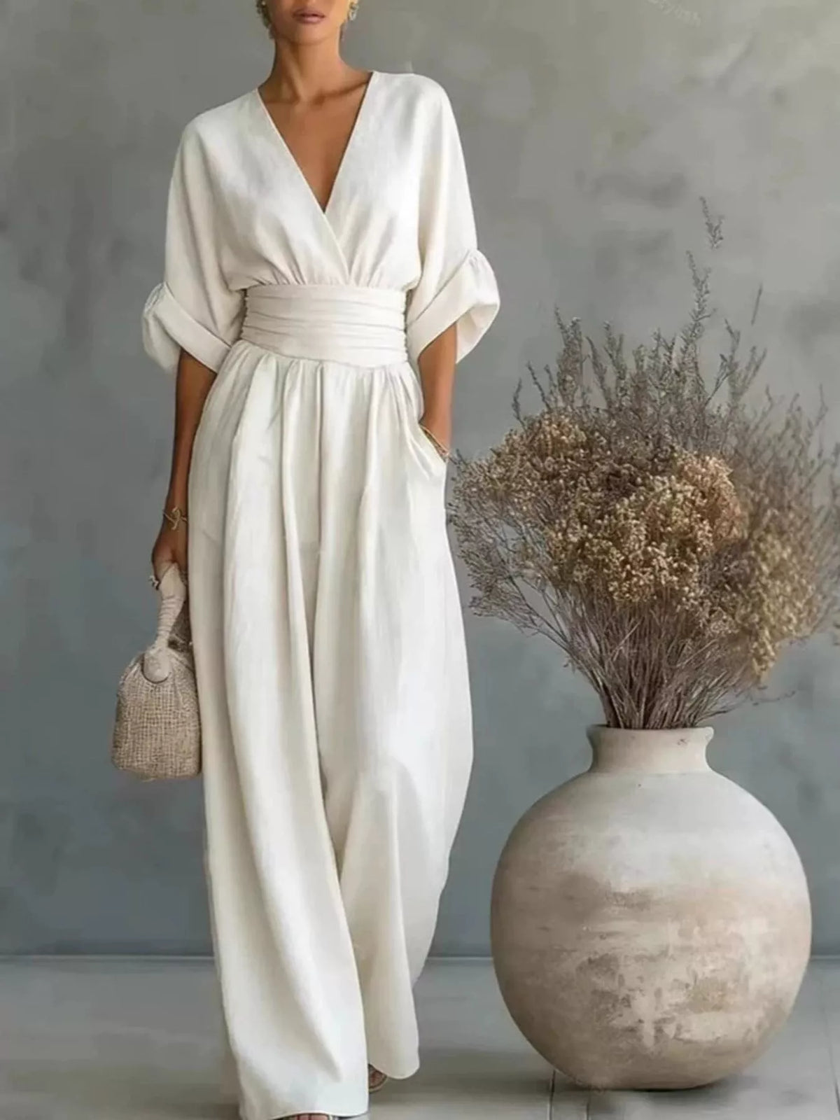 White wide-leg jumpsuit with V-neck, draped half sleeves, and cinched waist