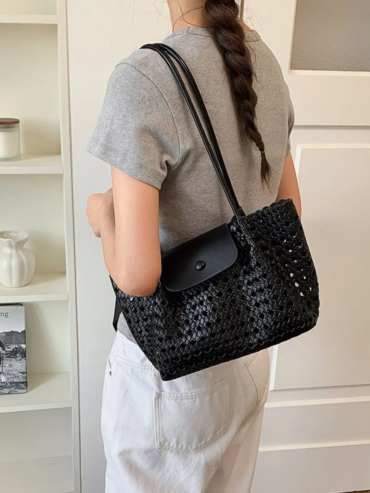 Medium black hollow-out vegan leather shoulder bag on model, long straps and snap flap front